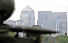Photograph of a missile system in the foreground and the Canary Wharf skyline in the background.