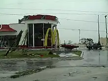 Photograph of a fast food restaurant showing some damage to its façade with debris on the adjacent road