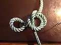 Step 3 of tying Cross constrictor knot: simple knot side loop folded over the middle loop