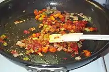 Brownish onions with carrots and celery in a frying pan.