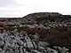 A mound of rough gritstone on a summit of stone and heather