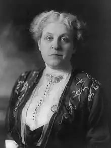 A black-and-white portrait of a woman from the belly up. She is wearing clothing common to the early 20th century and has a short haircut.