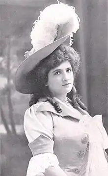 A young white woman, wearing a large hat with a white plume.