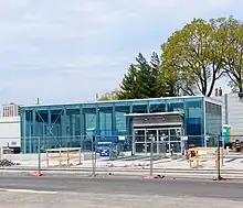 Photo of a largely completed modern light rail station entrance with glass panelling.