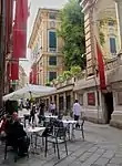 Narrow street lined by four storied buildings.