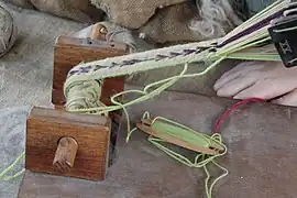 Belt or band shuttle, a short shuttle used for inkle weaving. This extra-sturdy shuttle is also used at a batten, to beat the newly-woven weft against the previously-woven fell.