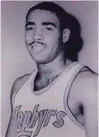 A man, wearing white basketball jersey with the word "ZEPHYRS" on the front, is posing for a photo.