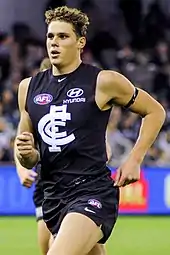 Male athlete in sleeveless guernsey runs during a football match