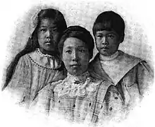 An Asian-American mother and her two children in a formal portrait; the daughter and son are about 11 and 9 years old, respectively; the daughter has long dark hair, the son has dark hair cut short with bangs; the mother's dark hair is in an updo, and she is wearing a high lace collar.