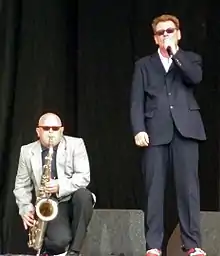 Thompson crouched onstage playing his saxophone, with Smash standing next to him singing into a microphone