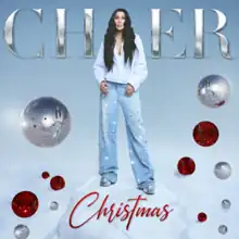 A computer graphic of Cher surrounded by large Christmas tree ornaments