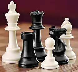 A selection of white and black chess pieces on a checkered surface.