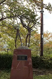 Sculpture of three lithe girls are playing with hoops, one girl appears to be flying.