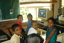 Indian hildren smiling in front of a computer