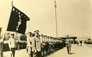 Sepia image of soldiers standing in formation for review, facing camera.