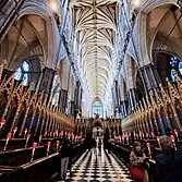 A long corridor with rows of gilded wooden stalls either side, facing each other.