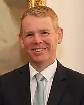 A smiling man wearing a dark business suit and tie