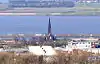 A distant view of a stone church with a tall steeple