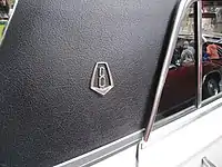 V8 badge as fitted to VC Valiant V8 sedan rear roof pillars and wagon front guards.