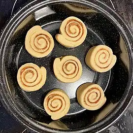 7 raw cinnamon rolls in a round pan, with some space between them to allow for expansion
