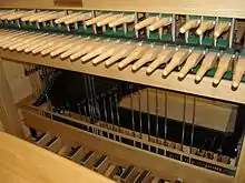A wooden keyboard of batons connected to a pedal board.