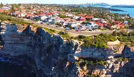 Sydney Harbour in distance as seen aloft from Tasman Sea, overlooking the clifftop suburb of Vaucluse.