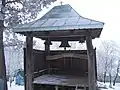 A fixed wooden semantron beneath bells at Căpuşneni church, Romania