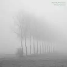 A photograph of a row of dead trees, obscured by a dense fog.