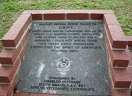 Code talker memorial with etched words: "Navajo Indian Code Talkers USMC. Used their native language skills to direct US Marine Corps Artillery fire during WWII in Pacific area. Japanese could not break code. Thus these early Americans exemplified the spirit of America's fighting men. Sponsored by: Disabled Veterans South Marion DAV#85 serving veterans and dependents." The memorial also includes the United States Marine Corps emblem.