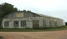 Photo of an old factory building with a fading sign that reads "Colby Cheese Factory"