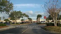 The parking lot of an outdoor shopping mall. Visible are two stop signs, several cars, and palm trees, along with signage reading "Bath & Body Works" and "Ross Dress for Less".