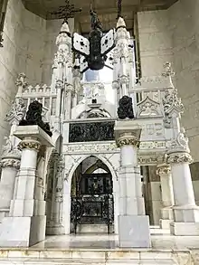 A large white, black, and gold tomb elaborately adorned with sculpture and writing, claiming to be the resting place of Cristobal Colon