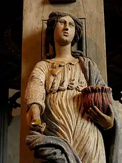 A wood carving, an allegory for "Charity",  on one of the five pillars supporting the baldachin.