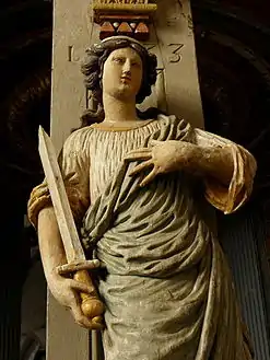 A wood carving, an allegory for "Justice" on one of the five pillars supporting the baldachin.