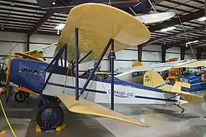 Command-Aire 3C3 open cockpit biplane with blue fuselage and cream coloured flying surfaces, in hangar