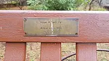 A plaque on a bench with the text "'Have a seat pet' Annie Inglis MBE 1922 - 2010"