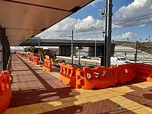Brick paltform with construction barriers and machinery on tracks indicating platform is under construction