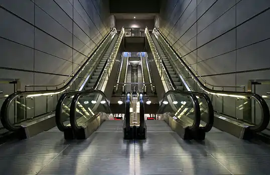 Four escalators, two going up and two going down. In the background are another four escalators.