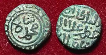 Front and back of copper coin with raised inscription, against a red background