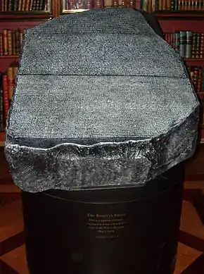 "Replica of the Rosetta Stone in the King's Library of the British Museum as it would have appeared to 19th century visitors, open to the air, held in a cradle that is at a slight angle from the horizontal and available to touch"