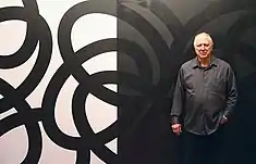 Corey Postiglione, in front of his black-and-white, site-specific painting, Population 5, at his exhibition of the same name.