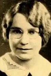 A young white woman with wavy blond hair, wearing eyeglasses