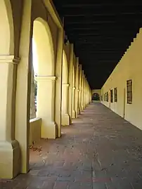 A view looking down an exterior corridor at Mission San Fernando Rey de España, a common architectural feature of the Spanish Missions