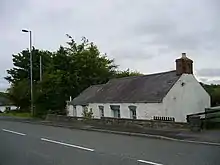 white painted single storey cottage with slate roof