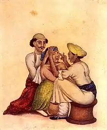 Historical color illustration of an Indian surgeon performing a couching procedure on a seated patient, while an assistant steadies the patient's head from behind.
