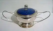 Shiny silver bowl with two elongated handles and a bright blue lid.