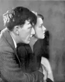 Young white man and woman in right profile, he embracing her, their hands clasped together
