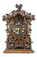 Carved spring-driven, mantel clock with bone hands, Gordian Hettich Sohn, Furtwangen, ca. 1870 (Deutsches Uhrenmuseum)