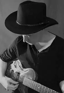 man playing guitar with hat on
