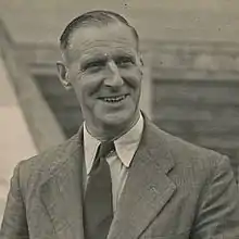 A photograph of a man with grey hair wearing a suit.